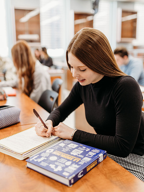 Une étudiante travaillant sur ses manuels dans une classe.