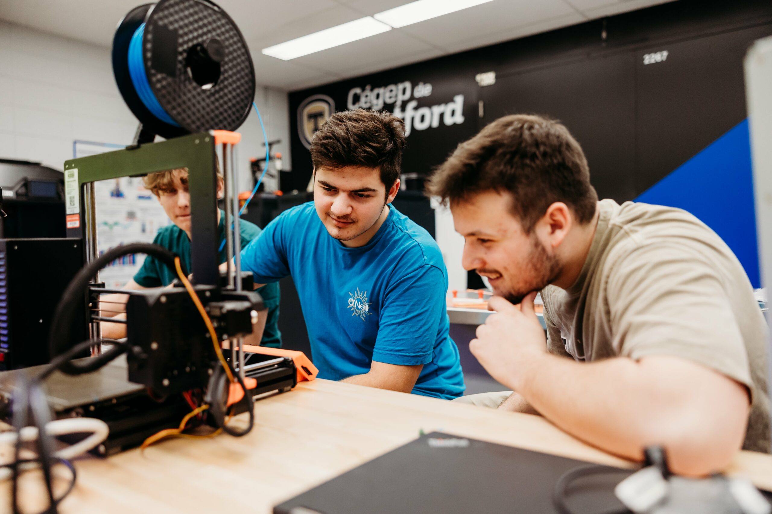 Trois étudiants analysent un appareil technologique dans une classe du Cégep de Thetford.
