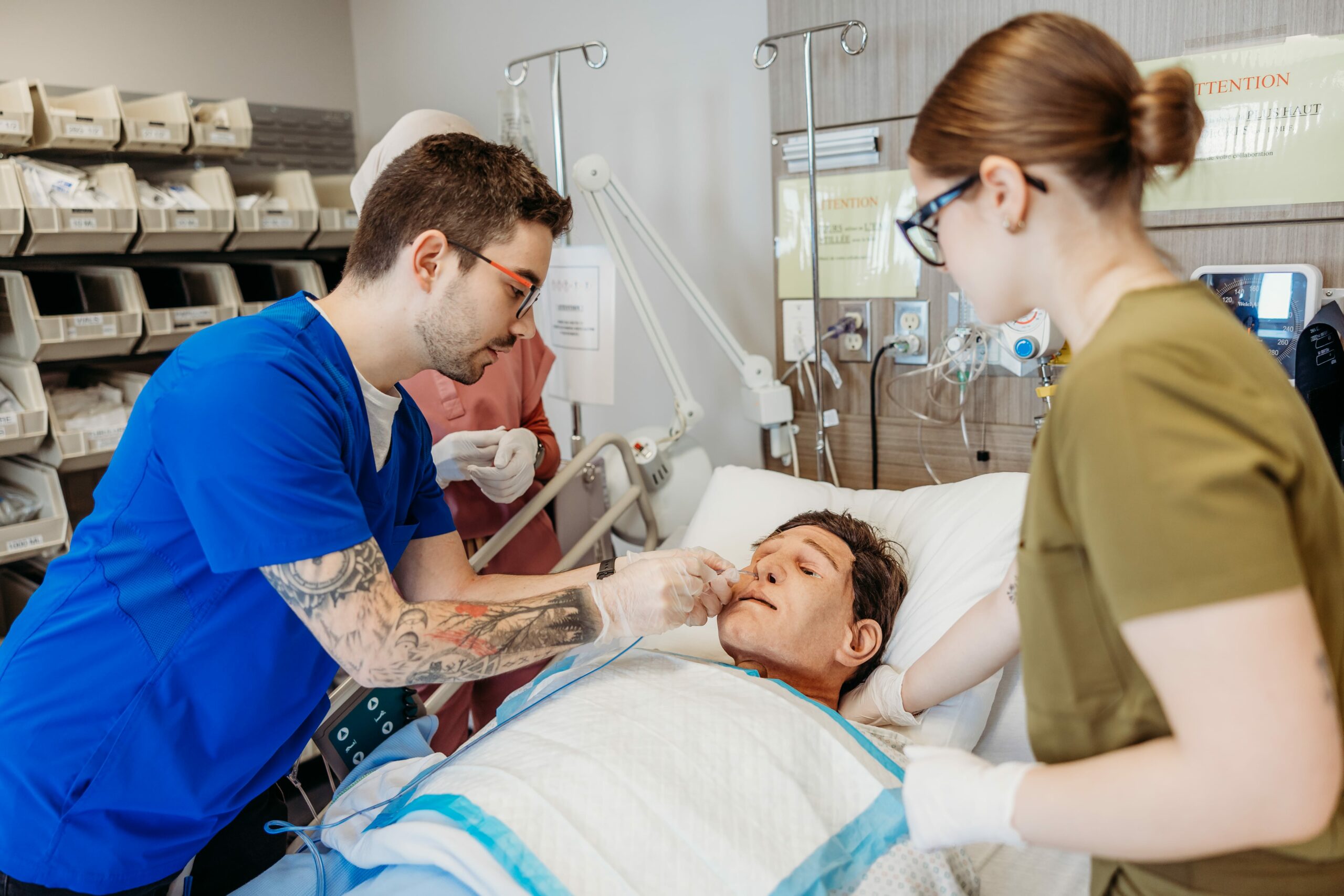 Deux intervenants en soins infirmiers simulent des procédures médicales sur un mannequin.