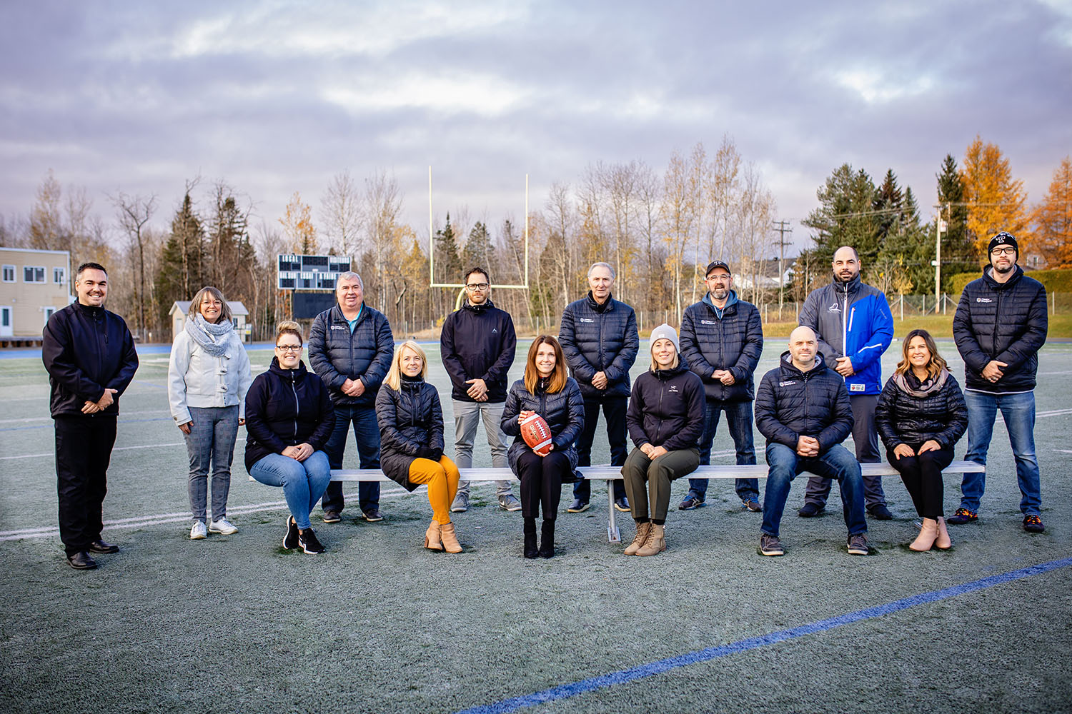 Photo de groupe de plusieurs responsables d'un programme sportif sur un terrain de football en automne.